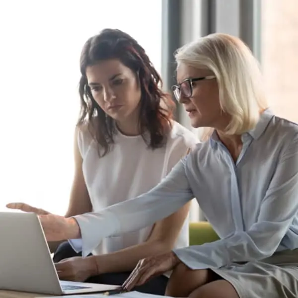 woman showing colleague a report on her laptop